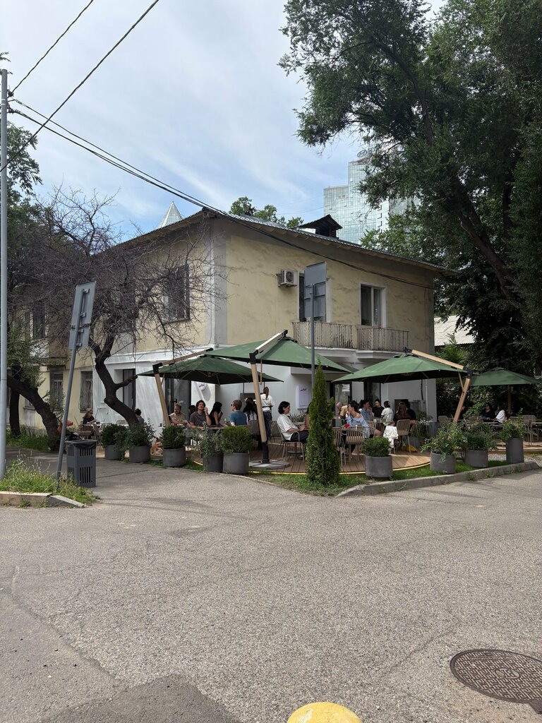 Летняя терраса кофейни под зелёными зонтами